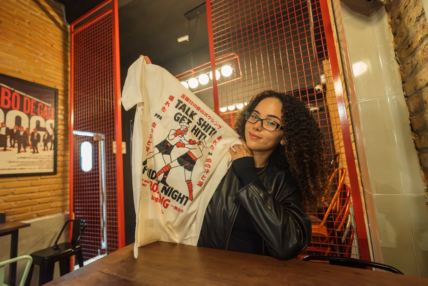 Rai mostrando uma camiseta em uma experiência de marca